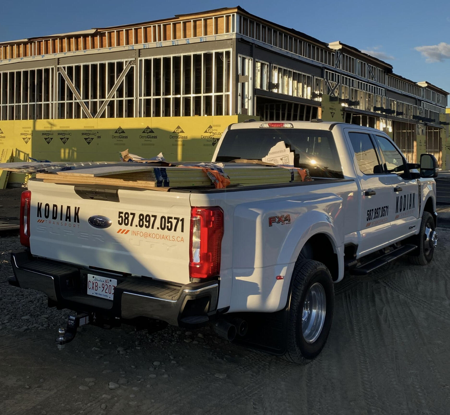 Kodiak Transport F-350 dually hauling building materials at a Calgary construction site.